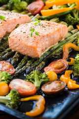 Fototapeta na wymiar Baked salmon and vegetables on baking tray