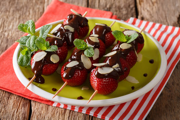 Strawberry dessert with chocolate, mint and almonds close-up on a plate. horizontal