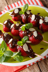 Skewers with fresh strawberries are decorated with chocolate, mint and almonds. vertical