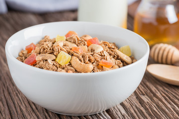 Granola with dried fruits and nuts in white bowl.