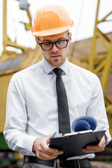 Engineer builder in a helmet holds drawings at construction site