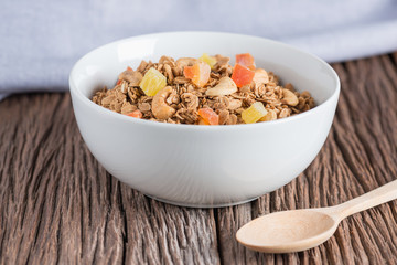 Granola with dried fruits and nuts in white bowl.