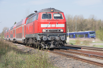 Fototapeta na wymiar Roter Triebwagen zieht Eisenbahnwaggon