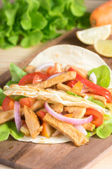 Grilled meat with onion and bell peppers, tomato,lettuce and serve with flour tortilla on wooden board.