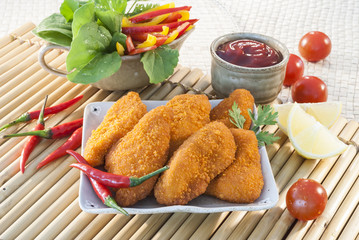 Spicy Breaded chicken fillets with red chilly lemon and cherry tomatoes with ketchup and bell pepper salads