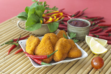 Spicy Breaded chicken fillets with red chilly lemon and cherry tomatoes with ketchup and bell pepper salads