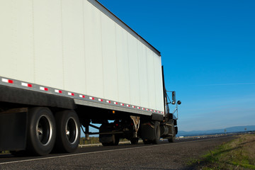Big truck and trailer on the road with skyline and blue sky background
