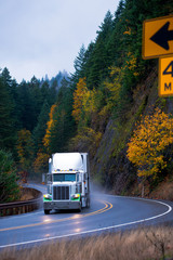 Semi truck in rain on windy autumn highway turn