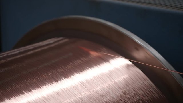 Close-up copper thread getting wound on cable drum in cable factory