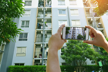 Businesswoman holding smartphone taking pictures view of condominium for rent in the green city