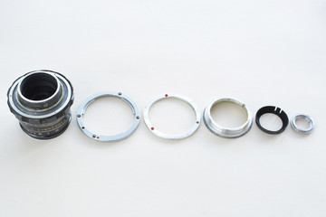 Details of the old manual lens, free space. A disassembled lens lined up in a row on a white...