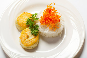 cutlets with herbs and rice on a plate. White background