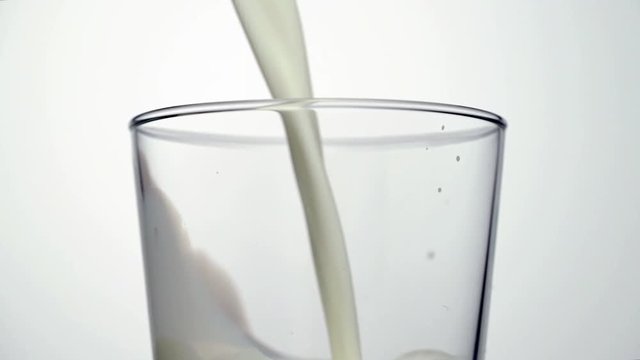 Macro shot of female hand taking jug of milk and pouring into empty glass