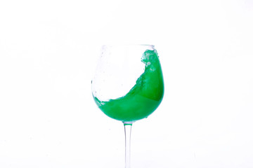 Green water splashes in a wineglass
