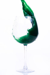 Green and violet water splashes in a wineglass