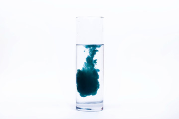 Blue paint falls in a glass with water