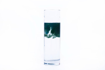 Blue paint falls in a glass with water