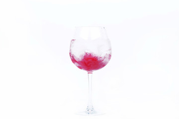Pink paint falls in a wineglass with water