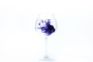 Violet paint falls in a wineglass with water