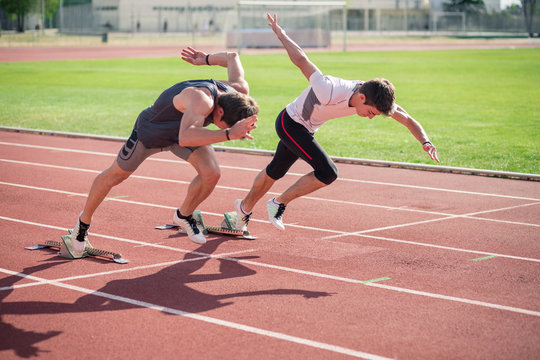 Two young  athletes running from the crouch start on race track