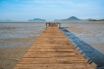 Wood bridge over land extends into the sea during ebb tide time
