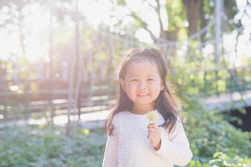 Happy kid in nature,little girl in white dress,playing on the suspension bridge  in the city park during warm summer