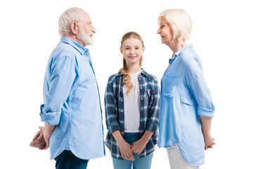 happy grandfather, grandmother and granddaughter standing isolated on white in studio