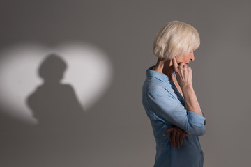 senior woman standing in studio with heart shaped shadow