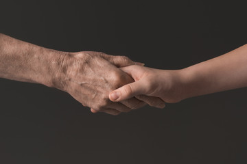 cropped view of people holding hands isolated on grey, young and senior people concept