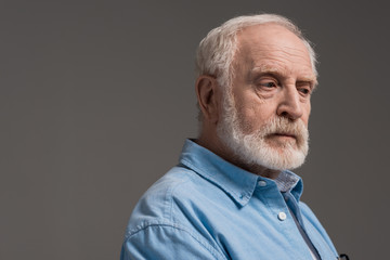 portrait of senior bearded man isolated on grey in studio