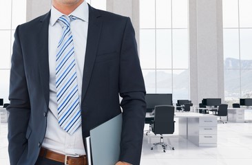 Businessman is holding note book against office background 
