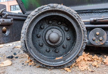 A very worn and blackened wheel from a road asphalt laying machine.