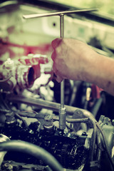 The hand is repairing the piston engine.