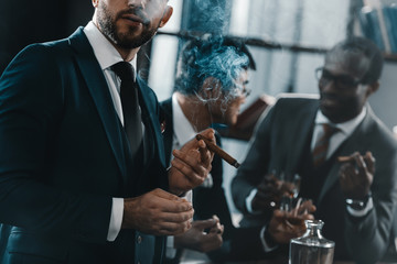 businessman smoking cigar with multicultural business team spending time behind - obrazy, fototapety, plakaty
