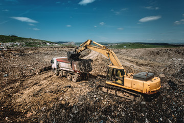 Industrial excavator loading dumper trucks with garbage © aboutmomentsimages