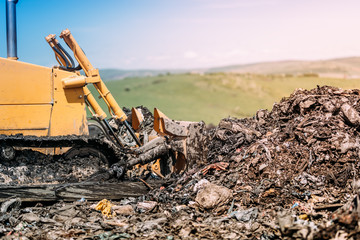 Fototapeta premium industrial bulldozer leveling garbage grounds. Heavy duty machinery working on construction site