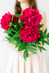 Happy young woman holding bouquet of peonies in hands. Sweet romantic moment