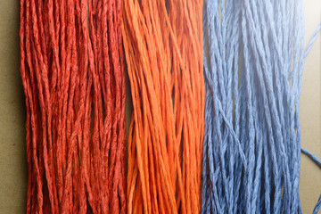 Paper thread for embroidery and a fragment of embroidery on the background of the canvas. Selective focus. Close-up.