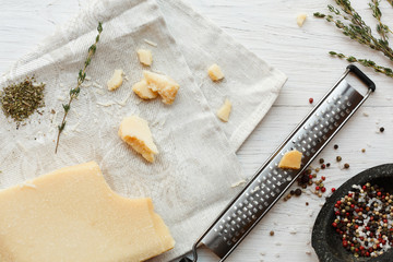 Parmesan piece with small grater and herbs top view