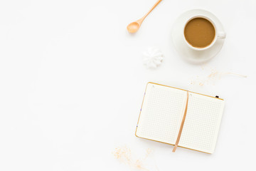 Desk workspace with cup of coffee, notebook, empty blank, cookie, died flowers on white background. Top view, flat lay, copy space.