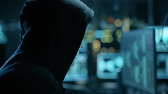 Masked Hacktivist Organizes malware Attack on Global Scale. They're in Underground Secret Location Surrounded by Displays and Cables. Shot on RED EPIC-W 8K Helium Cinema Camera.