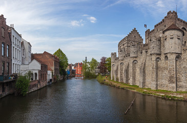 Fototapeta premium Panoramic view of medieval Gravensteen castle and canal with old picturesque traditional houses in historic part of Ghent, Belgium