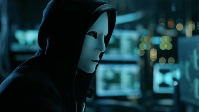 Masked Hacktivist Organizes malware Virus Attack on Global Scale. They're in Underground Secret Location Surrounded by Displays and Cables.Shot on RED EPIC-W 8K Helium Cinema Camera.
