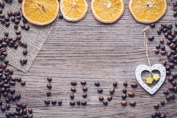 Coffee grains on a wooden surface with dried oranges and a wooden heart