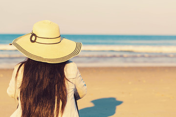 Woman in a hat sitting on the beach