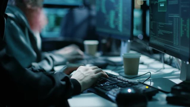 Team of Internationally Wanted Boy and Girl Hackers Organize Advanced Virus Attack on Corporate Servers. Place is Dark and Has Multiple displays. Shot on RED EPIC-W 8K Helium Cinema Camera.