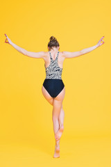 Obraz premium Young fit woman gymnast one leg balance pose isolated on yellow background