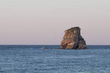 Naklejka premium Lonely rock island at sunset (Hendaye, France).
