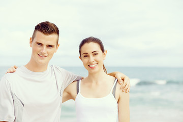 Young couple looking at camera while standing next to each other on beach