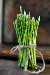 Hip of asparagus standing on wooden board.